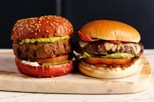 two hamburgers sitting on a wooden cutting board at Leonardo Hotel Southampton in Southampton