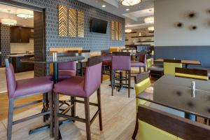 een restaurant met paarse stoelen en tafels en een tv bij Drury Inn & Suites Pittsburgh Airport Settlers Ridge in Pittsburgh