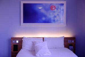 Hotel Nova Rooms Atlanta Shopping في سورات: سرير ومخدات بيضاء وصورة على الحائط