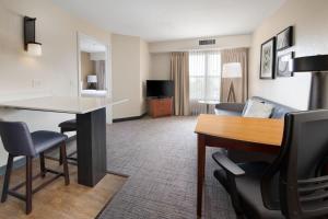 une chambre d'hôtel avec une table et un salon dans l'établissement Residence Inn by Marriott Rogers, à Rogers