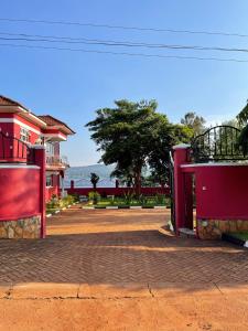 une cour avec deux bâtiments rouges et un arbre dans l'établissement The Jewel and the Lake, à Jinja