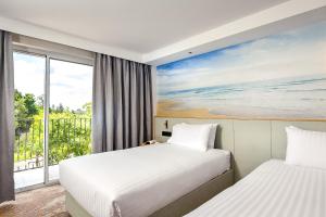 Aurea Hotel Perth Kings Park في بيرث: سريرين في غرفة الفندق مع نافذة