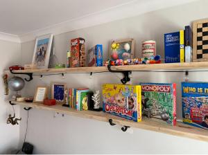 une étagère remplie de livres et de jouets sur un mur dans l'établissement West Wittering Family Home, à West Wittering