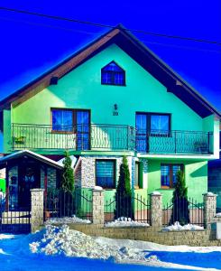 ein großes grünes Haus mit Balkon in der Unterkunft Homestay Renata in Nová Lesná