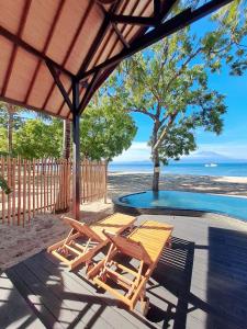 eine Terrasse mit 2 Stühlen, einem Tisch und einem Pool in der Unterkunft Beach House Penida in Nusa Penida