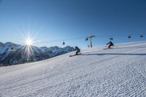 drie personen skiën over een sneeuwbedekte piste met een skilift bij Residence Iris in Valdaora