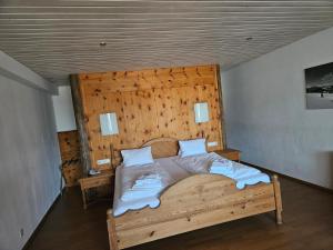 - une chambre avec un grand lit et une tête de lit en bois dans l'établissement Sporthotel Kogler, à Mittersill