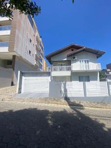 una casa bianca con cancelli bianchi e un edificio di Casa Ampla no Centro, Piso Térreo ou Superior a Bombinhas