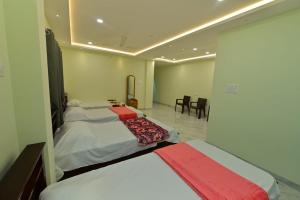 1 dormitorio con 2 camas, mesa y sillas en Gokula Homestay, en Subrahmanya