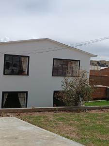 uma casa branca com três janelas e um quintal em Casa Jardin Copacabana em Copacabana