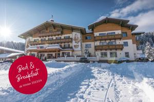 un edificio grande con mucha nieve delante en Hotel Taxerhof, en Radstadt