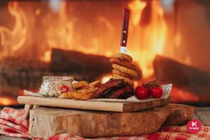 um prato de comida com um bife e batatas fritas em frente a uma fogueira em Hotel Krvavec em Cerklje na Gorenjskem