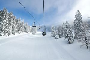 um teleférico que sobe uma pista coberta de neve em Hotel Krvavec em Cerklje na Gorenjskem