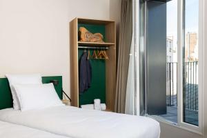 1 dormitorio con cama, ventana y armario en Best Western 11BAUER Paris Saint-Ouen, en Saint-Ouen