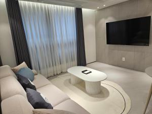 a living room with a white couch and a tv at HOTEL THE DESIGNERS LYJ SUITE YEOKSAM in Seoul