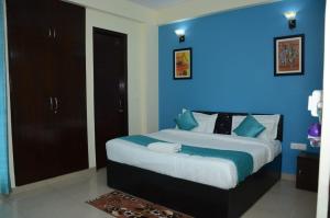 a bedroom with a large bed with a blue wall at Rumaisa Red in Noida