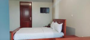 um quarto com uma cama e uma televisão na parede em SEED HOTEL em Entebbe