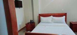 um quarto com uma cama e um telefone numa mesa de cabeceira em SEED HOTEL em Entebbe