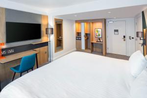 グロスターにあるHoliday Inn Gloucester - Cheltenham, an IHG Hotelの大型ベッドとテレビが備わるホテルルームです。