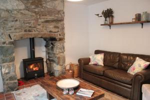 een woonkamer met een bank en een open haard bij Terfyn Cottage in Dinorwic