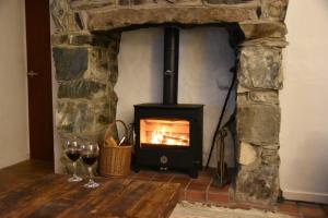 een stenen open haard met twee glazen wijn bij Terfyn Cottage in Dinorwic