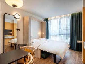 1 dormitorio con cama, mesa y espejo en Aparthotel Adagio access Hamburg, en Hamburgo