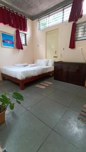 1 dormitorio con 1 cama grande y cortinas rojas en Wow Farm House, en Auroville