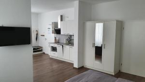 a white kitchen with white cabinets and a refrigerator at Neckarzeit in Neckarwestheim