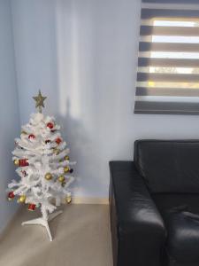 - un arbre de Noël blanc dans un salon avec un canapé dans l'établissement Paradise Village Port Aventuras, à Salou