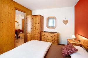 Schlafzimmer mit einem Bett, einer Kommode und einem Spiegel in der Unterkunft Chalet Primula 9 in Santa Caterina Valfurva