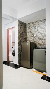 a kitchen with a refrigerator and a brick wall at Maya Homes in Naivasha