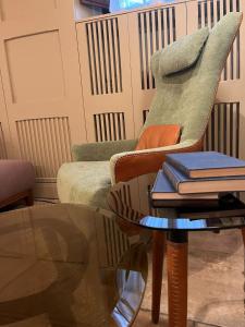 ein Wohnzimmer mit einem Stuhl und einem Tisch mit Büchern in der Unterkunft Hotel Nizza in Florenz