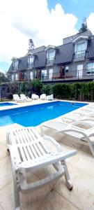 un grupo de tumbonas blancas y una piscina en Be mas apartamentos boutique Villa Gral Belgrano, en Villa General Belgrano