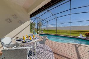 d'une terrasse avec une table et des chaises à côté de la piscine. dans l'établissement Dream Villa - New 4BR/3BA - 6 Miles From Disney, à Orlando