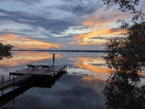 eine Person, die bei Sonnenuntergang auf einem Dock auf einem See steht in der Unterkunft 4 Guest Suite with Waterfront Views at Fancie's PEC - Suite 2 in Belleville