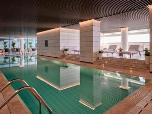 una piscina con sedie e tavoli in un edificio di Grand Hyatt Kuwait Residences a Kuwait