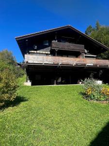 un bâtiment avec un banc au-dessus d'une pelouse dans l'établissement Ferienwohnung Zirbelweg, à Siegsdorf