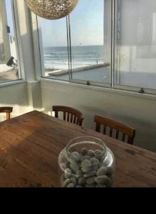 a table with a bowl of rocks on it with a view of the ocean at Playa Norte Experience in Punta Hermosa