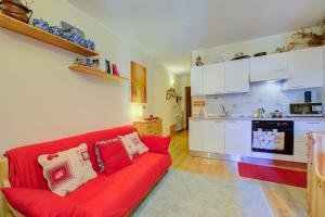 a living room with a red couch and a kitchen at Studio Grange Nest Ski & Relax - Happy Rentals in Sestriere