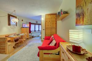 a living room with a red couch and a dining room at Studio Grange Nest Ski & Relax - Happy Rentals in Sestriere