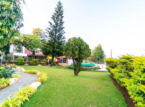 un parque con césped verde y árboles y un edificio en Treebo Raval Resort with Valley View, en Panchgani