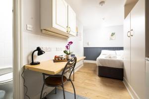 a small room with a desk and a bed at Charmstay Swiss Cottage in London