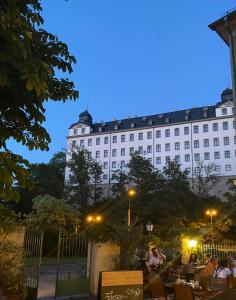 um grande edifício branco com pessoas sentadas à sua frente em Haus Heiken Apartment Sonnenblume em Altenburg