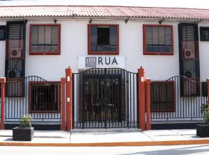 a gate in front of a building with a rua sign at Rua Hoteles Talara in Talara