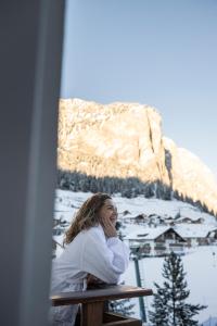 une femme assise à une table devant une remontée mécanique dans l'établissement Hotel Acadia - Adults Mountain Home, à Selva di Val Gardena