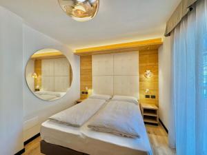 a bedroom with a large bed and a round mirror at Cesa Planber Apartments Mountain View SKI-IN SKI-OUT in Canazei