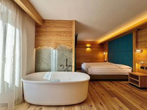 a bathroom with a bath tub and a bed at Cesa Planber Apartments Mountain View SKI-IN SKI-OUT in Canazei