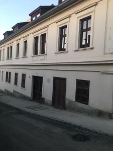 - un bâtiment blanc avec portes et fenêtres donnant sur une rue dans l'établissement Sziklai Apartman, à Veszprém