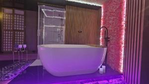 a bathroom with a large tub in a pink room at Grey Aqua Secret Apartament in Gdańsk