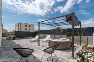 a patio with a hot tub and chairs at luxury apartment with garden jacuzzi in Trogir